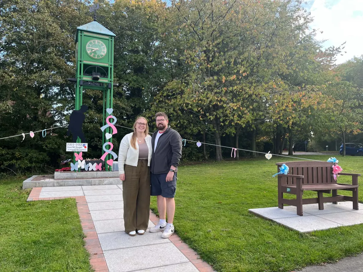 Two people standing beside the ribbon display at the green Priorslee clock tower